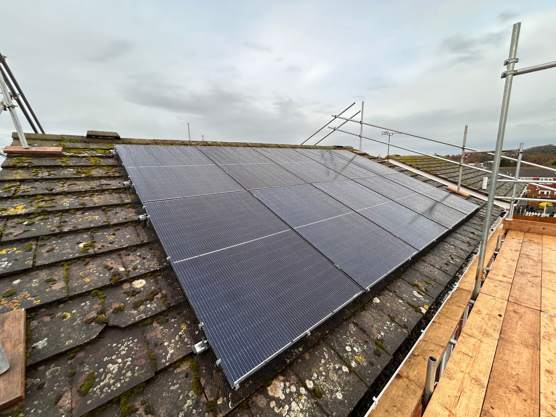 Solar panels installed on a slate residential roof with scaffolding and walkway