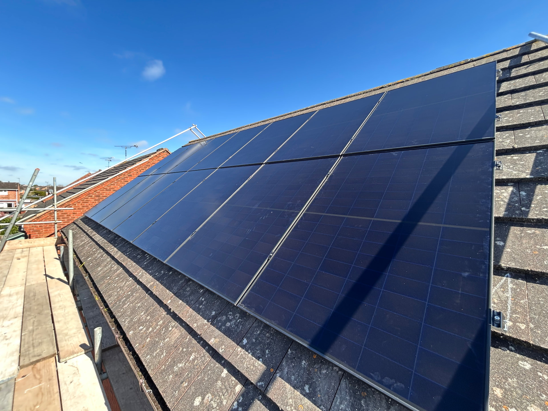 Wide dark-panel solar array on a slate residential roof