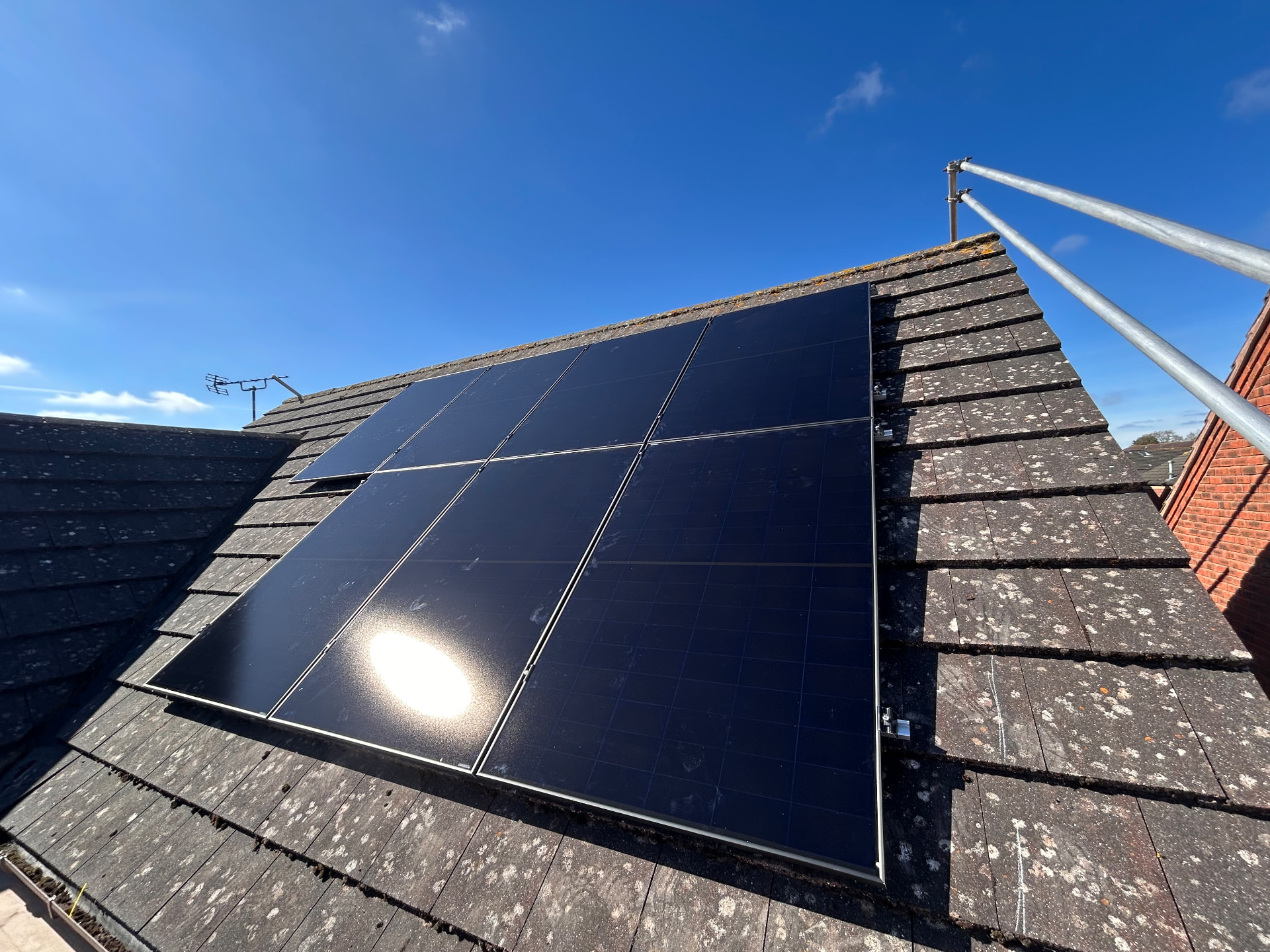 Close-up of dark solar panels fitted to a slate roof under a blue sky