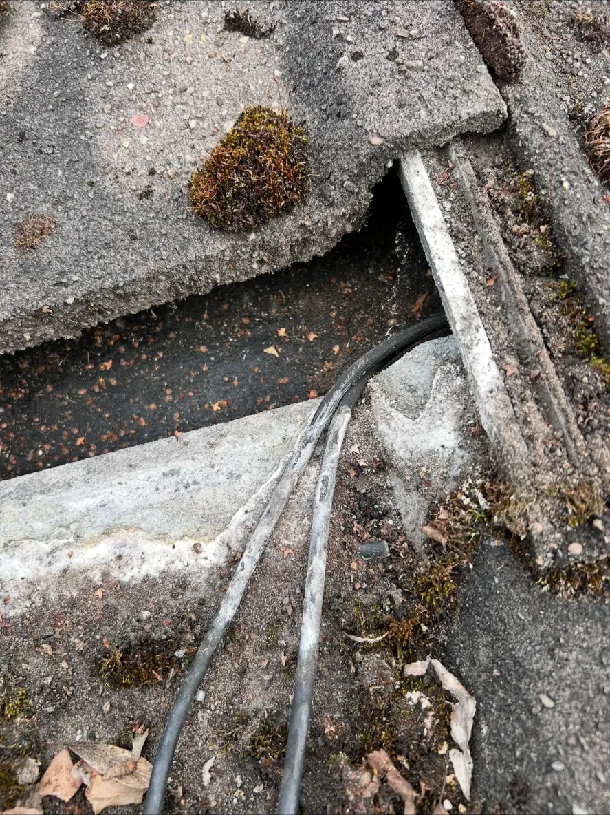 Damaged cable insulation beside a broken roof tile